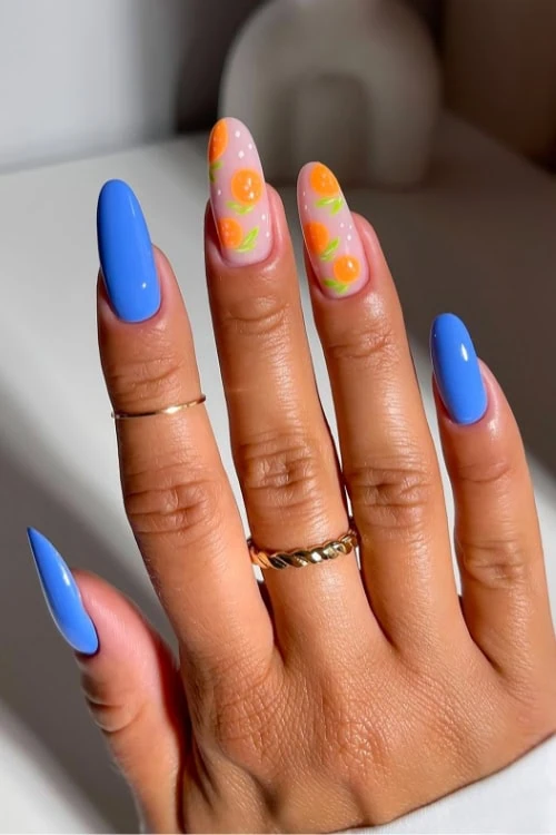hand with blue nails with orange fruit nail art