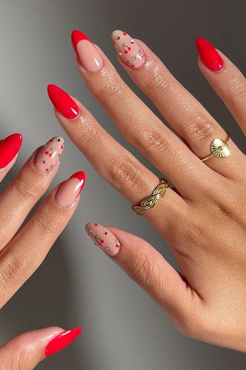 hand with red nails with cherries and rhinestones nail art