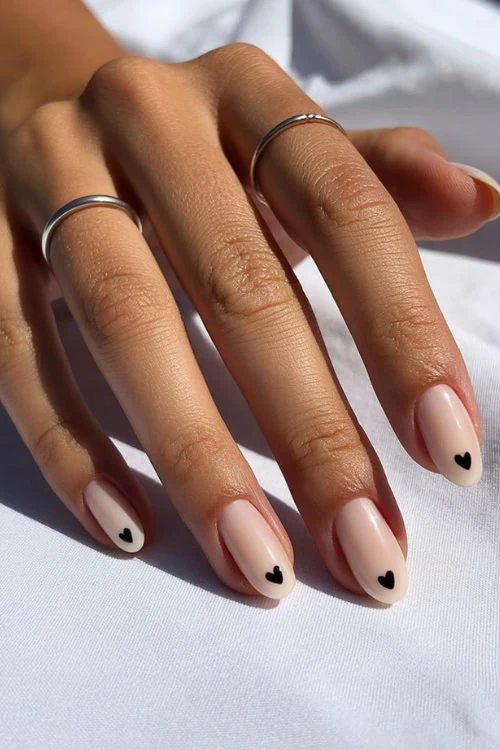 hand with short almond shaped nails with tiny black heart on each