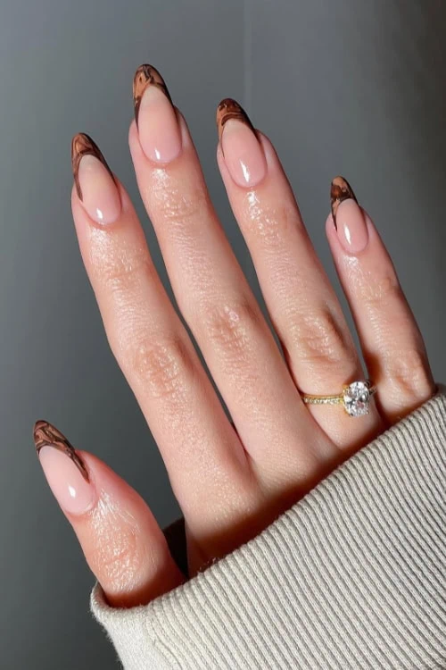 female hand with brown marbled french tip nails for fall