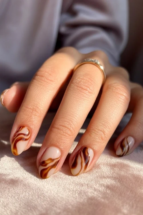 female hand with minimalist fall nails with brown swirls