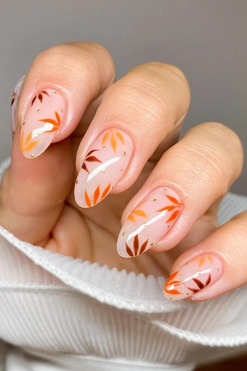 female hand with fall nails that have a floral leaf pattern