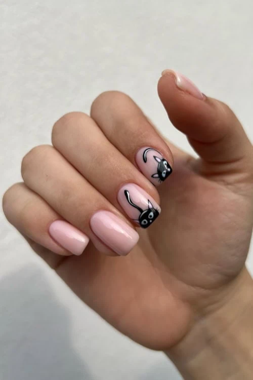 female hand with black cats painted on the nails for halloween