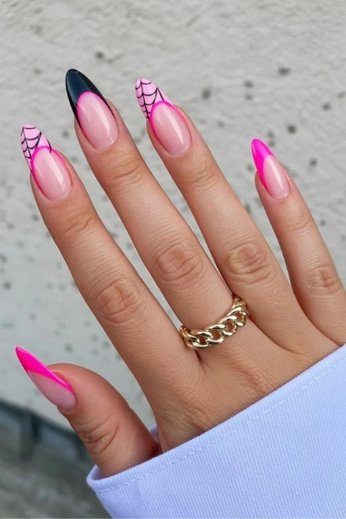 female hand with neon pink and black nails for halloween