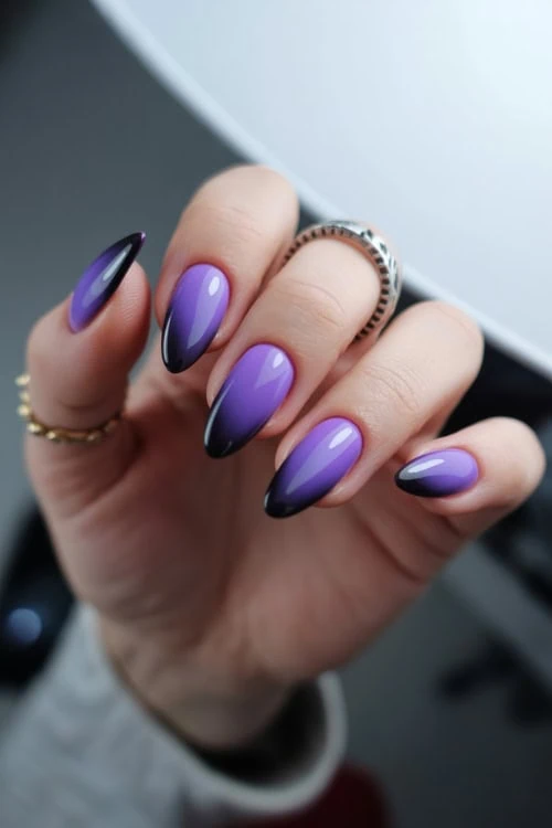 female hand with purple and black ombre nails for halloween