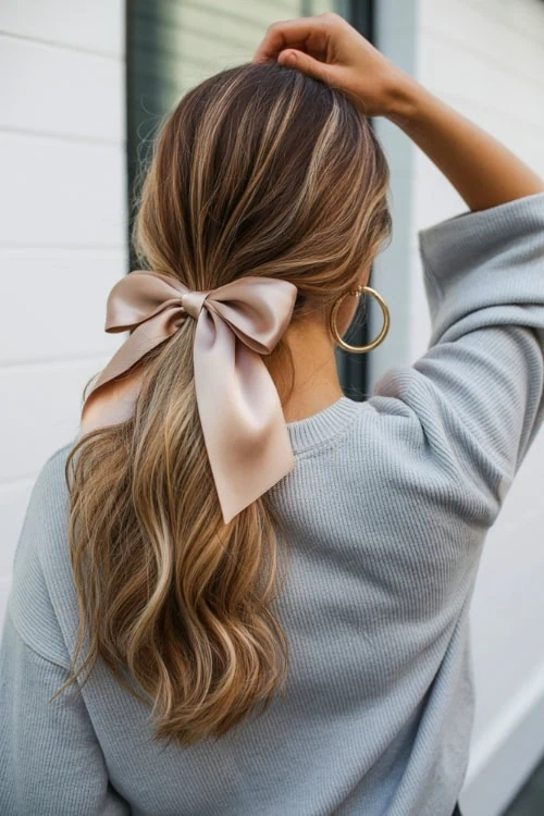 back of a woman's head with a low ponytail and ribbon