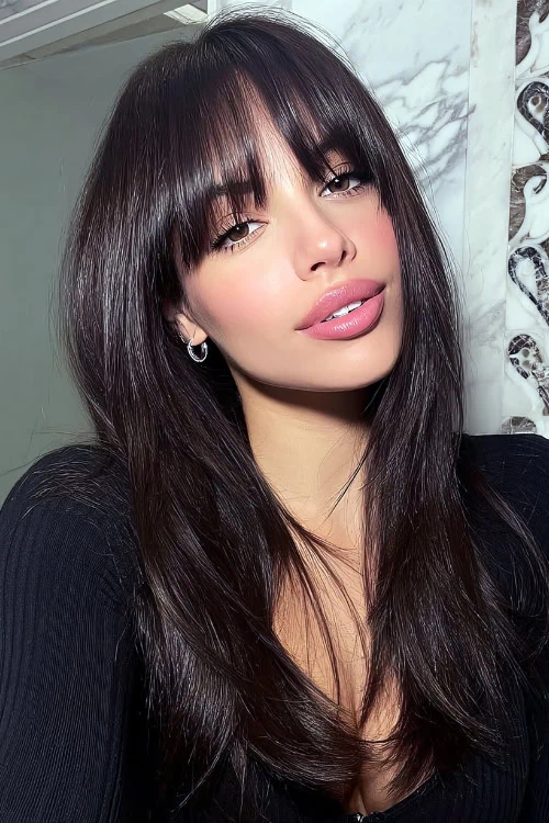 woman with dark hair that is layered with bangs