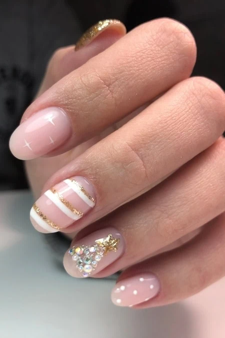 Elegant nude and white gel manicure with gold accents and sparkling rhinestones