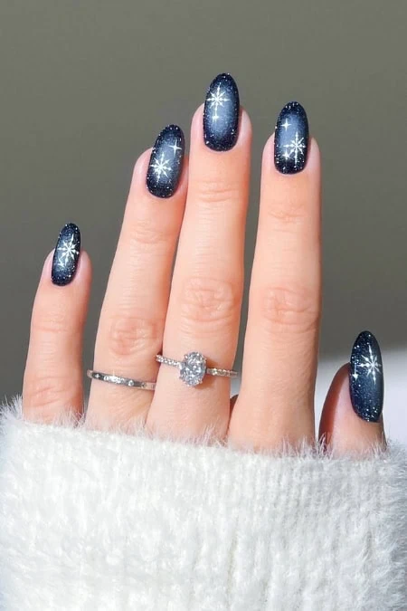 Dark blue glitter nail polish with starburst design for winter Christmas holiday nail art.