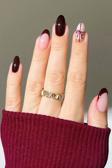 Elegant manicured nails with Christmas-themed accent nail, featuring deep burgundy and pink shades for holiday nails inspiration.