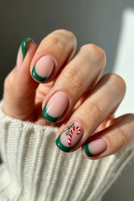 Festive Christmas nail art with green French tips and candy cane accent design, perfect for holiday season nails.