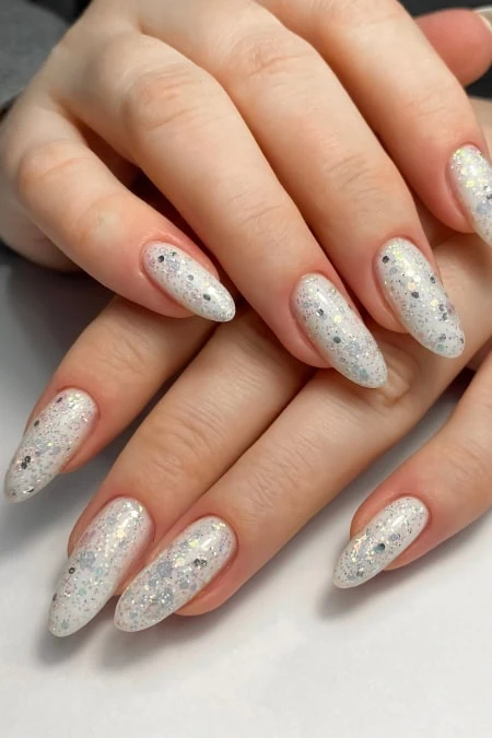 Silver glitter nail art with holographic sparkle and almond-shaped manicure