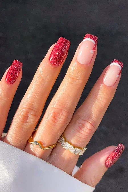 Sparkly red Christmas nail polish with elegant French tips on manicured nails, showcasing holiday-inspired nail art and trendy gel nail designs.