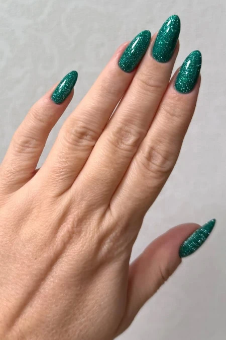 Shimmering green gel manicure on well-groomed nails for a trendy and elegant beauty look for Christmas