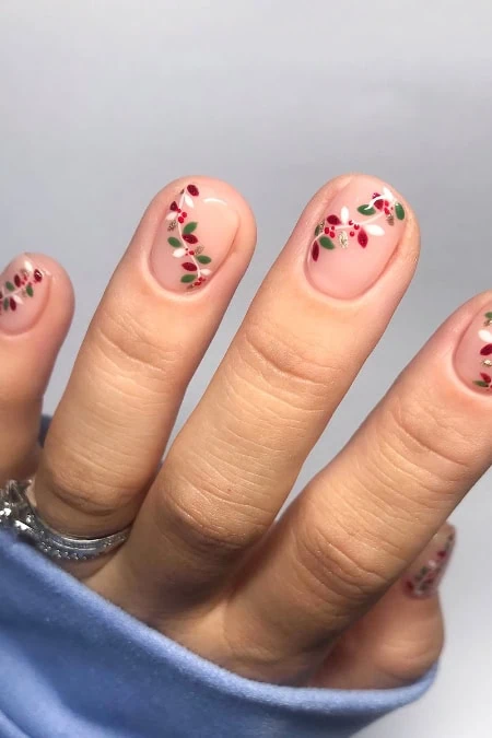 Delicate floral nail art with red and green holiday-themed designs