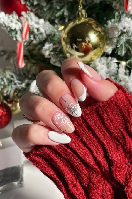 Elegant holiday nail art with white and silver snowflake designs on manicured nails, perfect for Christmas celebrations.