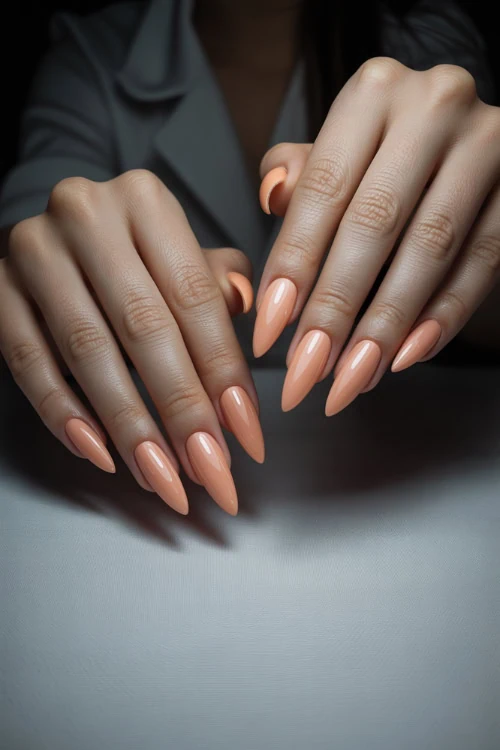 Glamorous manicure with peach almond-shaped nails, perfect for elegant beauty and nail art inspiration.