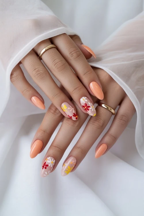 Beautiful manicured nails with floral nail art and peach-colored polish, showcasing professional nail design and manicure trends.