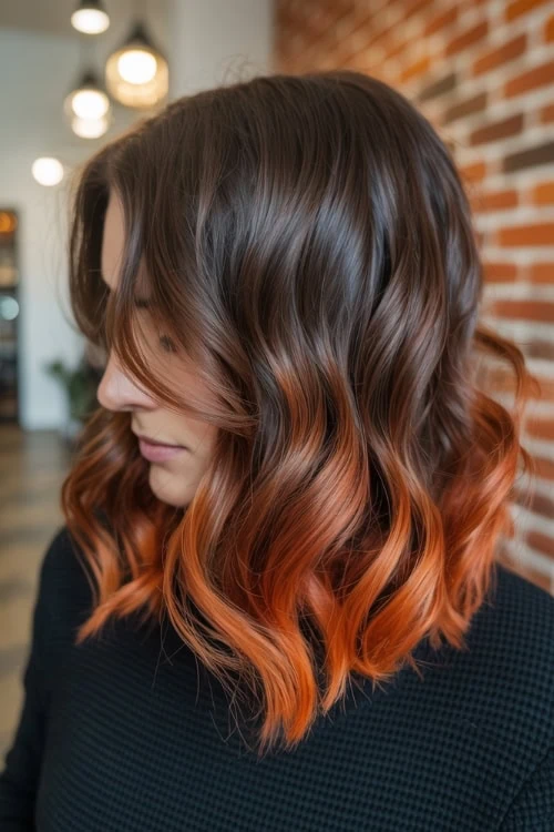 Vibrant ombre red and brown wavy hairstyle on woman with shoulder-length hair, perfect for hair coloring and styling inspiration for fall.