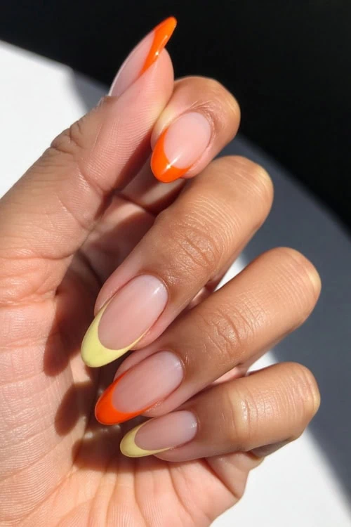 Colorful almond-shaped French design manicure with vibrant orange and yellow tips, perfect for spring and summer nail fashion.