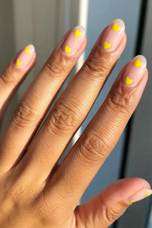 Bright yellow heart nail art on natural nails, perfect for summer and special occasions, showcasing trendy and cute manicure designs for a stylish look.
