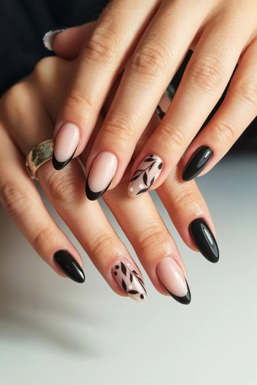 Beautiful professional nail art with black and nude French tips and floral accent nails on manicured hands.