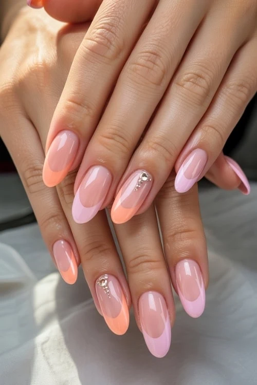 Elegant pastel pink and peach ombre nail art with rhinestone accents, perfect for a stylish and sophisticated look.