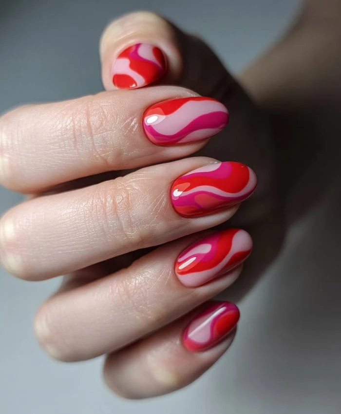 Vibrant red and pink marble nail art design with glossy finish, perfect for summer and special occasions.