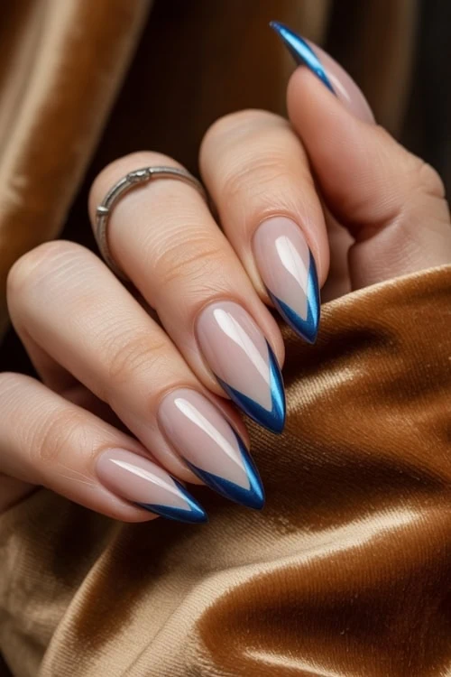 Elegant blue and nude acrylic French tip nail design with sharp stiletto tips on manicured fingers.
