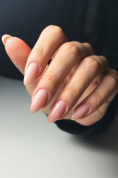 Elegant manicured nails with a soft pink gel polish, perfect for a sophisticated beauty look.