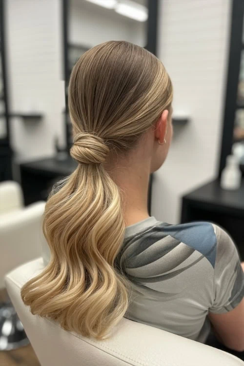 Blonde hair styled in loose waves with a low twisted ponytail, showcasing elegant and healthy hair for beauty and hair care enthusiasts.