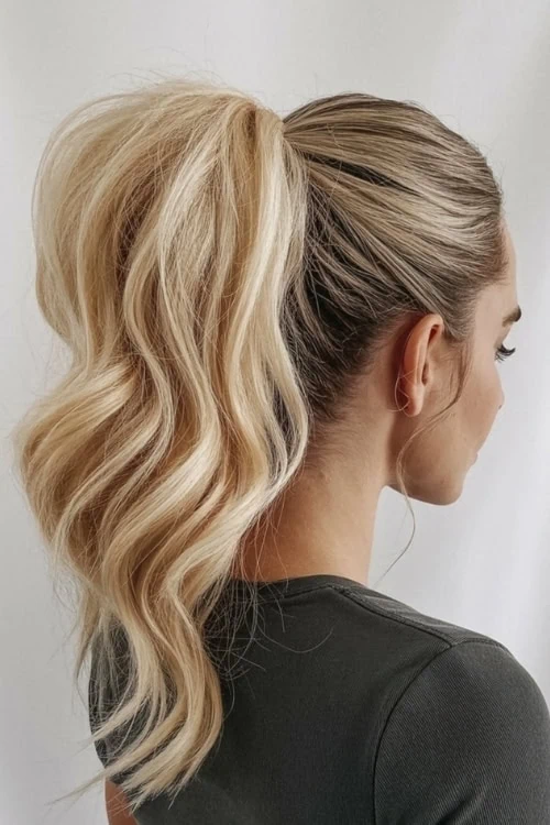 Vibrant blonde hair styled in loose curls with a sleek, high ponytail for a trendy and polished look.