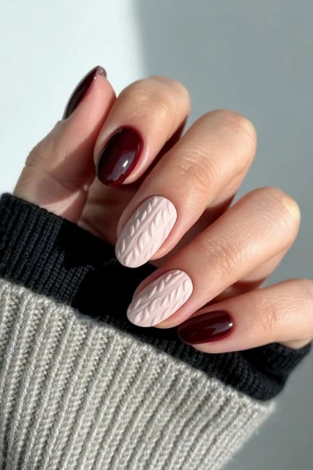 Chic manicured nails with burgundy and soft pink cable knit textured nail design showcasing stylish nail art for winter or fall fashion.