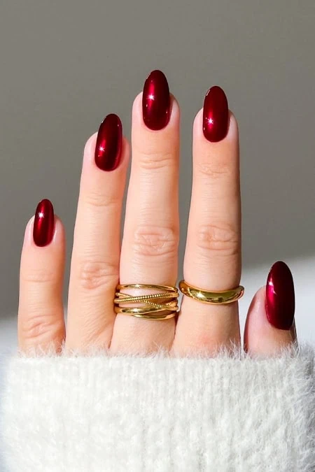 Shiny red winter manicure with gold rings on fingers, close-up of well-groomed nails, perfect for beauty and nail art, style, and elegance.