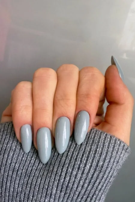 Elegant gray acrylic nail manicure with almond-shaped tips on a well-groomed hand. Perfect for a chic, modern look, showcasing professional nail art and beauty care.