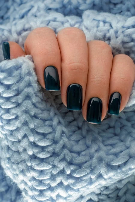 Polished black manicure with glossy nails on cozy blue knitted blanket, perfect for beauty, nail care, and seasonal style inspiration.