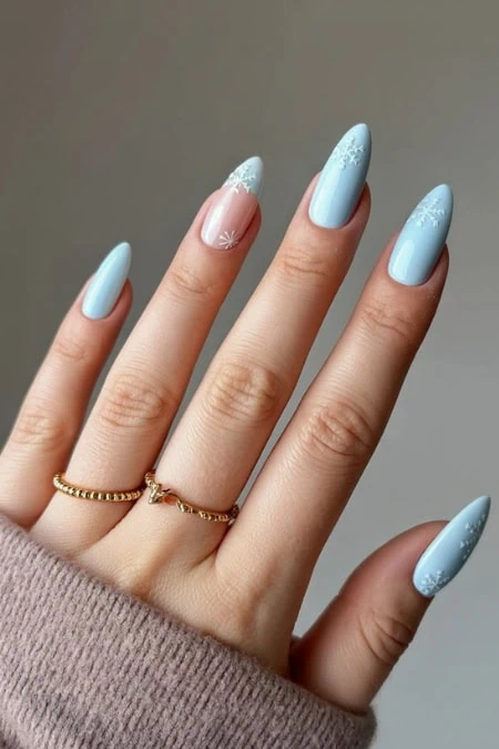Elegant pastel blue nail art with delicate white snowflake designs for a sophisticated winter-inspired nails and manicure. Perfect for a stylish, seasonal look.