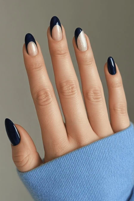 Vibrant navy blue and glitter nail polish manicure on female hand with manicured fingernails, styled with a cozy blue sweater. Perfect for beauty and nail care enthusiasts, showcasing elegant and trendy nail art.