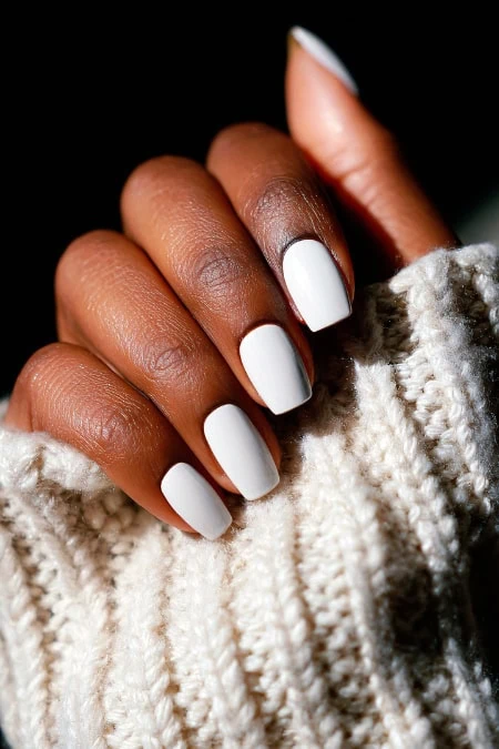 Elegant hand with manicured winter white nails, cozy knitted sweater, close-up of nail care, beauty and self-care, perfect for skincare, nail art, and beauty tips.