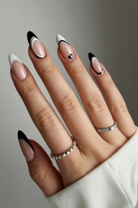 Elegant manicured nails with black and white geometric nail art on well-groomed fingers, showcasing fashionable acrylic nail design and stylish jewelry for a modern beauty look.