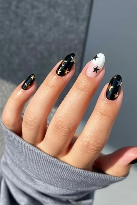 Black and white star-themed nail art with glossy finish, perfect for trendy chic looks and special occasions. Featuring detailed nail design with celestial motifs for stylish beauty enhancement.