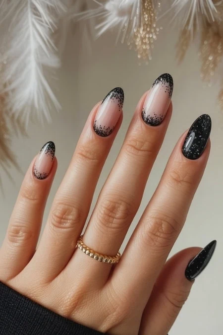 Elegant black and nude ombré gel nail art with sparkle accents on manicured fingernails, showcasing stylish nail design, perfect for beauty and fashion lovers.
