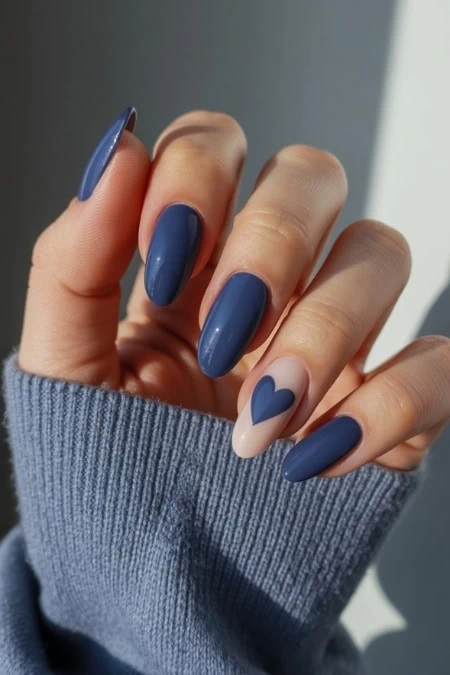 Blue and beige nail art with a heart design on a manicured hand, showcasing modern nail gel polish and trendy manicure styles.