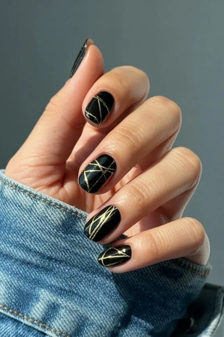 Glossy black and gold geometric nail art, stylish manicure featuring modern design and elegant detail.