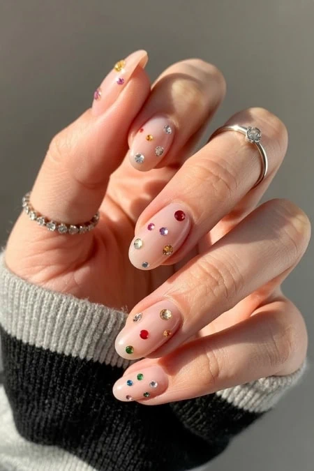 Colorful jeweled nail art manicure with sparkling gemstones on natural nails, perfect for trendy new years beauty, fashion, and jewelry enthusiasts.