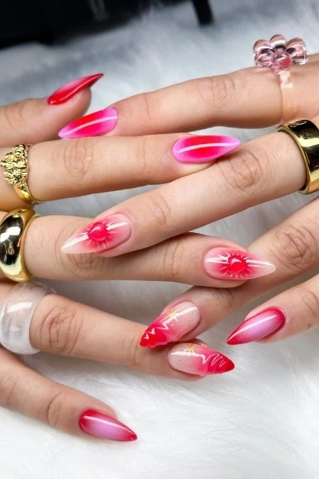 Bright pink and red ombre stiletto nails design for Valentine's day with floral accents, showcasing trendy, luxurious manicures for beauty and fashion enthusiasts.