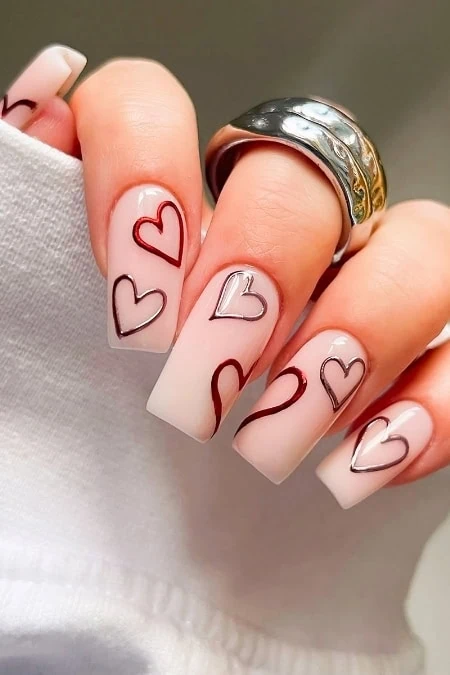 Delicate French manicure with heart nail art and silver rings, perfect for enhancing your beauty and nail design collection. Showcasing Valentine's Day inspired nails in an elegant and stylish way.