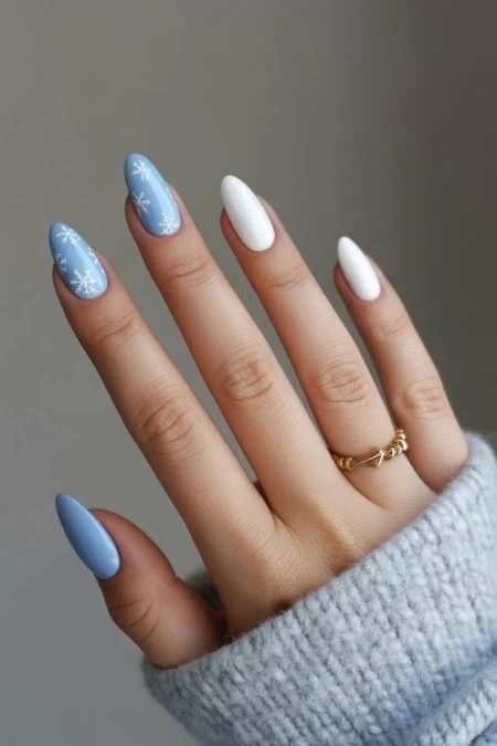 Blue and white winter-themed nail art with snowflake designs on acrylic nails, perfect for holiday season.