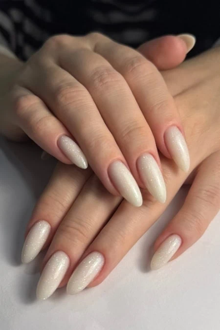 Beautiful almond-shaped nails with a subtle shimmer nail polish, perfect for elegant and stylish looks. The manicure showcases professional nail art design, ideal for beauty, wellness, and self-care enthusiasts.