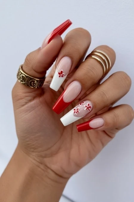 Vibrant red and white floral acrylic manicure with long coffin-shaped nails, perfect for stylish women seeking trendy nail art and professional nail design.